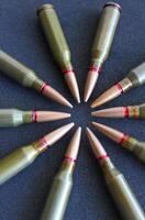 Combat bullets laid out in a circle shape on a black surface vertical stock photo