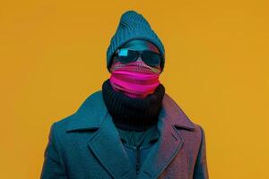 Handsome Fashion Model in Trendy Overcoat with Neon pink Ski Mask and Neon Yellow Background Modern Lifestyle Focus photo