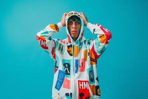 Trendy male model in a hoodie with graphics and a bright turquoise backdrop showcasing modern Males portrait fashion and casual lifestyle photo