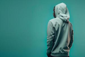 Fashionable male model in a hoodie with a light teal background captured for a casual yet stylish portrait that emphasizes contemporary trends and modern flair photo