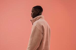 Modern male fashion model in a zip up jacket with a peach pink background showcasing a chic and fashionable lifestyle with a contemporary style photo