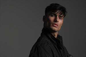 Fashionable male model in a zip up jacket with a charcoal gray background highlighting a sophisticated lifestyle and modern fashion portrait photo