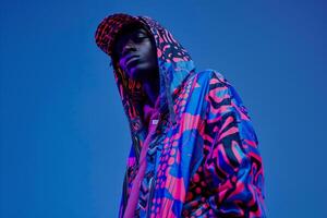 Chic male model in a printed hoodie with an electric blue background emphasizing stylish fashion and modern portrait photo