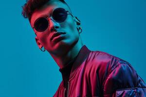 maroon zip up jacket and large round sunglassesmale dress withelectric blue Males backgroundFashion portrait photo
