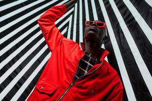 Bright Red Zip Up Jacket and Sporty Sunglasses on Male with Black and White Stripes Background Fashion portrait emphasizing Trendy Lifestyle photo