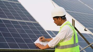 Indian engineer in protective helmet checks technical documentation of the solar station after installation video