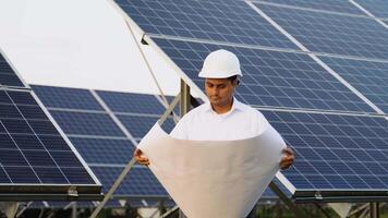 Indian engineer in protective helmet checks technical documentation of the solar station after installation video