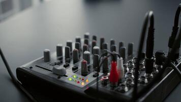 DJ mixer console with knobs and equalizer standing on home studio desk. Professional audio sound station electronic controller in living room recording space. Close up video