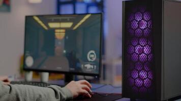 Close up of RGB powerful computer gamer rig with first-person shooter game on screen, pro cyber man participating at online esports championship. Player performing at gaming tournament in cyberspace video