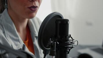 Popular internet live radio talk show host talking to public at microphone. Social media famous influencer recording podcast remote interview while sitting in living room studio. Close up video