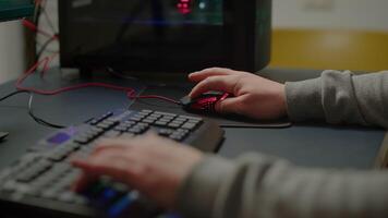 Close up hands shot of man player typing on RGB keyboard buttons while playing online shooter game. Virtual shooter game performing in cyberspace, esports gamer esports online tournament video