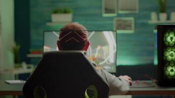 Back view of pro gamer testing new graphics of FPS videogame playing from home at professional powerful computer. Virtual shooter game performing in cyberspace, esports player gaming online tournament video