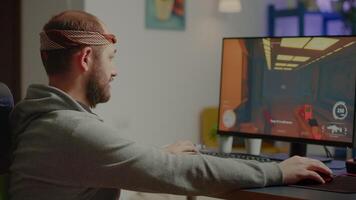 Pro man gamer turning head looking at camera smiling playing FPS shooter videogame during gaming championship in cyberspace. Esports player performing on powerful computer in online tournament video