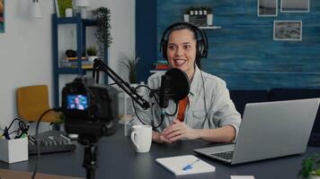 Famous social media influencer greeting internet public while starting to record daily vlog. Attractive digital content creator filming herself talking with audience while sitting at home studio desk. video