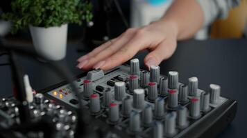 Internet famous star tweaking audio mixer knobs and buttons. Internet radio host changing volumes and using studio sound console equalizer to improve broadcast audio quality. Close up shoot video