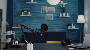 Empty home studio desk with professional audio equipment on table. Podcast broadcast desk having recording devices and gadgets inside living room with nobody in it. Studio shot video