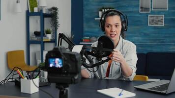 Tech enthusiast presenting VR wearable headset specifications to audience while recording in living room studio. Vlogger sitting at desk while reviewing futuristic virtual reality goggles. video