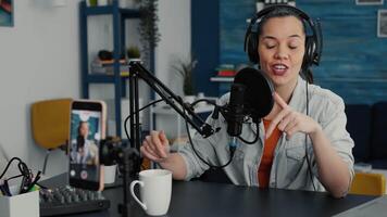 Famous influencer streaming remote podcast using smartphone while talking to audience. Attractive online live radio talk show host discussing last worldwide news and evens with public. video
