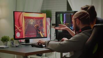Couple of gamers playing first person shooter videogame on RGB powerful computer screaming, supporting each other during online competition. Pro cyber man performing from home at virtual tournament video