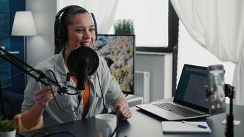 Smiling content creator starting to record vlog while putting on headphones in home studio. Social media influencer recording for audience while having professional audio equipment. video