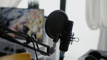 Professional microphone on stand installed in home studio. High tech recording condenser podcast device on empty living room equipped with electronic streaming equipment. Close up video