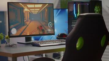 Empty room with RGB powerful personal computer for online videogames and gaming chair, first-person shooter game on screen. Cozy room with modern design is lit with warm and neon light. video