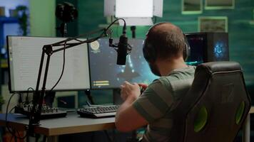 Man streamer playing space shooter games using professional RGB keyboard and wireless joystick. Pro gamer talking into microphone on streaming chat during online tournament video