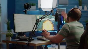 Videogame streamer losing online videogame competition wearing professional headset talking on stream chat. Sad gamer using powerful computer for gaming tournament late night playing space shooter game video