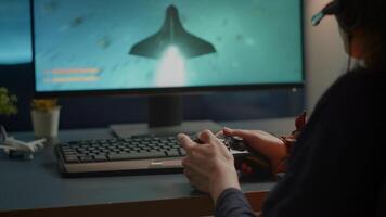 Closeup of competitive woman player holding joystick playing space shooter games at powerful computer late night. Professional gamer using wireless controller for online gaming championship video