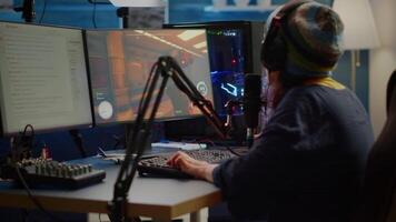 Streamer playing FPS videogames and talking with team mates on streaming open chat using professional microphone. Cyber performing in online tournament on RGB powerful computer in gaming sudio room video