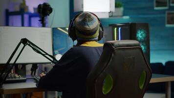 Back shot of pro gamer woman playing first person games using RGB keyboard in home studio. Gamer streaming gameplay using professional gaming powerful computer during online competition video