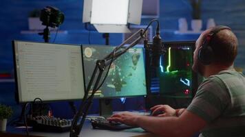 Competitive gamer with headphones using stream chat on powerful computer playing online shooter game late at night. Virtual online streaming cyber checking sound performing in gaming tournament video