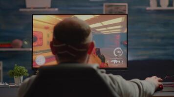 Back view of sad professional eSports gamer losing shooter mock-up game. Defeated man with headphones streaming online cyber performing during gaming tournament using powerful personal computer video