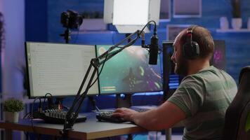 Streamer man talking with multiple players into headphones and winning games competition. Professional gamer streaming online videogames with new graphics on powerful computer from gaming room video