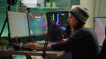 Professional woman streamer playing FPS games talking into microphone via streaming chat during online esports tournament. Gamer making online videogames with new graphics on powerful computer video