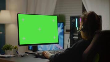 Pro gamer playing virtual game on powerful computer with green screen mock up, chroma key display. Cyber player using professional pc with isolated desktop streaming shooter games wearing headset video