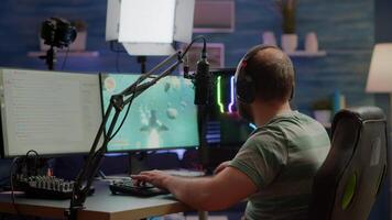 Excited streamer with headphones winning important online esport competition of space shooter playing on powerful computer. Professional pro gamer streaming videogames using professional microphone and headset video