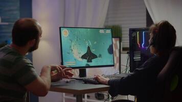 Nervous couple of cyber players screaming losing space shooter game during gaming tournament playing on powerful personal computer wearing professional headset performing in cybersport competition video