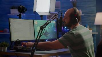 Man streamer cyber checking sound at mixer performing space shooter game on RGB powerful computer talking with players on stream chat and microphone in gaming competition. Player man streaming video