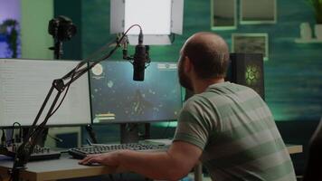 Streamer cyber performing space shooter game on RGB powerful computer talking with players on stream chat and microphone during professional competition. Player man streaming in home studio video