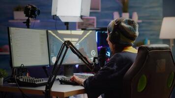 Pro streamer checking sound on mixer putting on headset and start playing FPS game during virtual competition. Gamer using professional streaming setup, stream chat in gaming home studio video