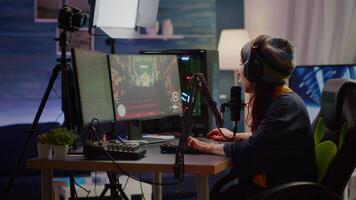 Woman streamer checking sound using professional mixer for streaming games in gaming home studio. Pro gamer playing first person shooter games talking with team mates on open chat video
