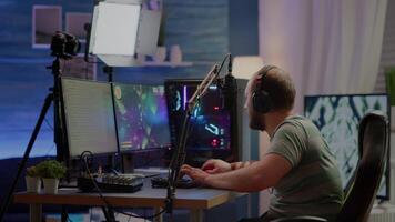 Happy streamer man winning space shooter online competition talking at professional microphone in gaming home studio. Gamer playing online games with streaming chat open during tournament video