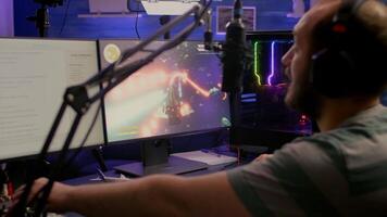 Pro gamer playing space shooter online games using RGB keyboard and mouse during virtual championship. Streamer looking into monitors, talking with team on streaming chat video