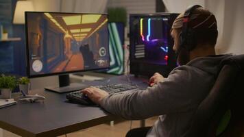 Videogamer winning first person shooter tournament using RGB keyboard and professional headphones. Pro player man talking with other players online for game competition on powerful computer video