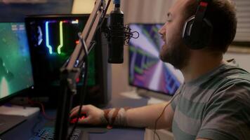 Pro gamer puts professional headphone and start playing space shooter game new graphics on powerful computer. Player using two monitors during online tournament at streaming hone studio video