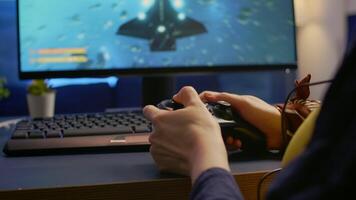 Close-up of professional cyber gamer playing space shooter game using wireless controller. Pro player use RGB equipment during gaming tournament late at night in home studio video