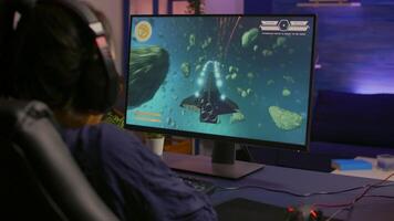 Back view of pro gamer winning space shooter game using headphones. Player using joystick for online championship sitting on gaming chair playing on professional powerful computer video