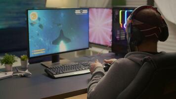 Back shot of pro gamer playing online space game on powerful computer using wireless controller. Competitive player man using professional RGB equipment during game tournament video