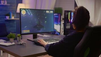 Pro gamer talking into microphone with other gamers during digital championship. Player wearing headphones and playing online games with new graphics on powerful computer from gaming room video
